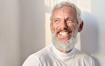 a smiling senior man in a white turtleneck sweater