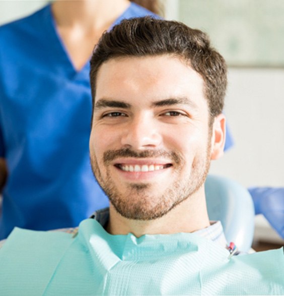 Male patient smiling in chair at oral surgeon’s office