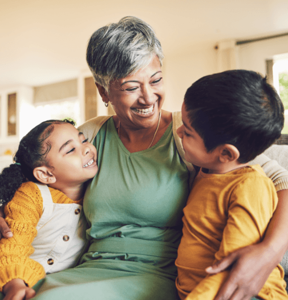 A woman sits on a couch with two children, discussing dental health and care in a cozy living room setting.