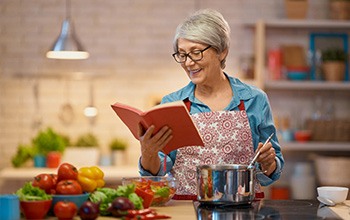 a person reading a cookbook and stirring a pot