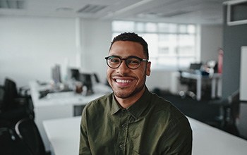 a smiling man sitting on a desk