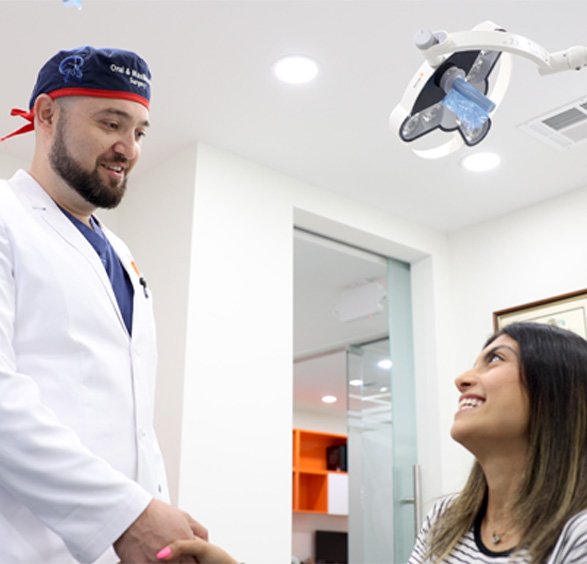 Woman in treatment chair smiling at her oral surgeon