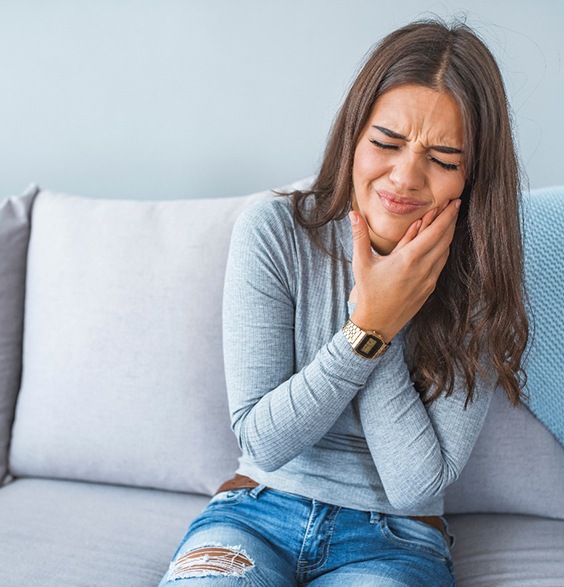 Woman wincing in pain and holding her cheek