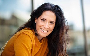 Woman in orange sweater smiling outdoors