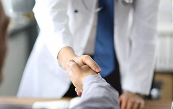 Patient shaking hands with an oral surgeon