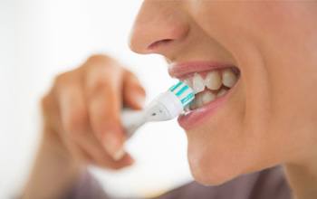 Person smiling while brushing their teeth