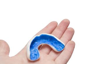 Holding a blue and white mouthguard for playing sports