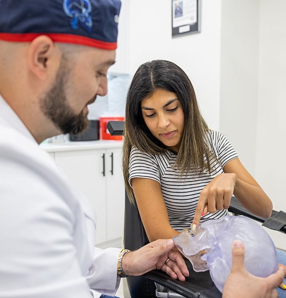 Oral and maxillofacial surgeon showing a patient a model of the skull