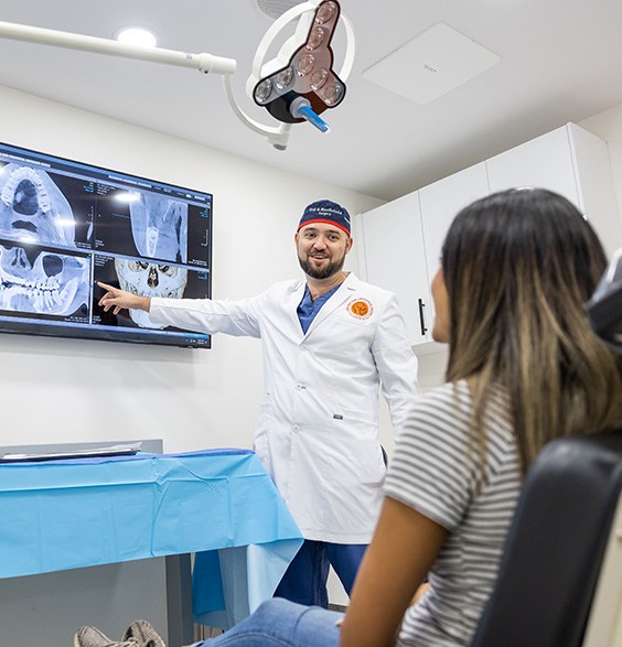 Oral and maxillofacial surgeon showing a patient x rays of their teeth