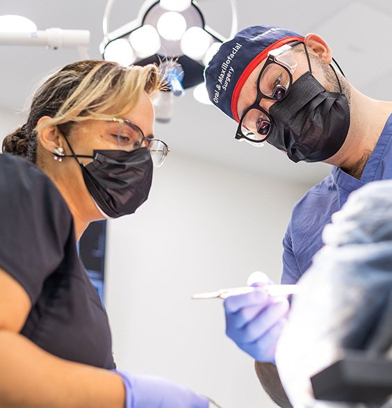 Oral surgeon and assistant treating a patient