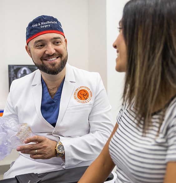 Oral surgeon smiling at a patient in the treatment chair