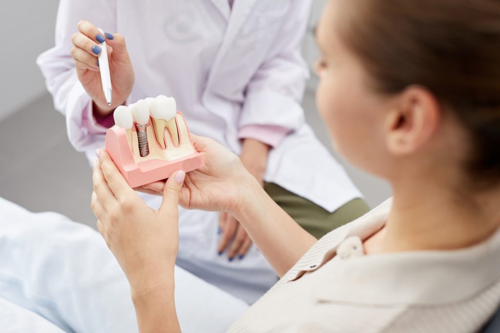 Patient with rheumatoid arthritis looking at model of dental implant