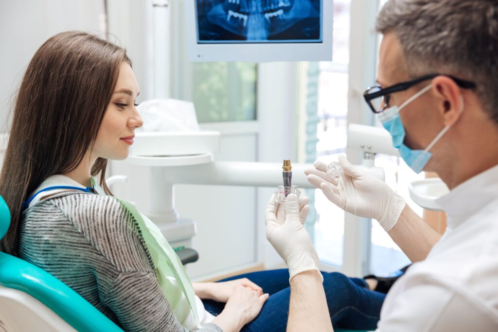 Dentist showing woman a sample dental implant