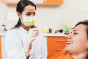 Patient smiling while dental team member holds an extracted tooth 